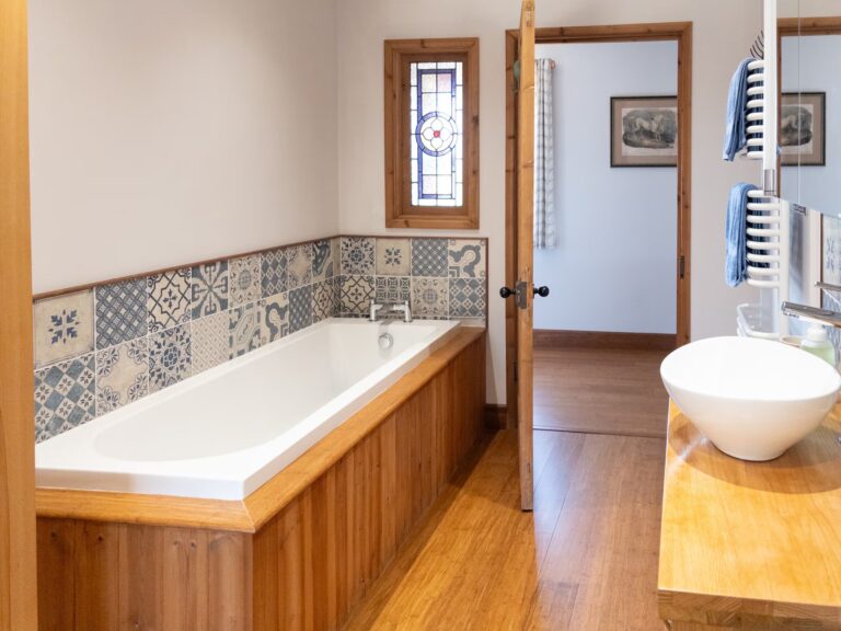 Full-size bath with wooden panelling and patterned tiles in the lodge bathroom
