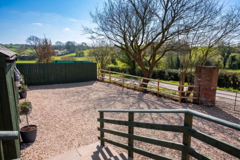 Private gravel parking area with a gate and countryside views